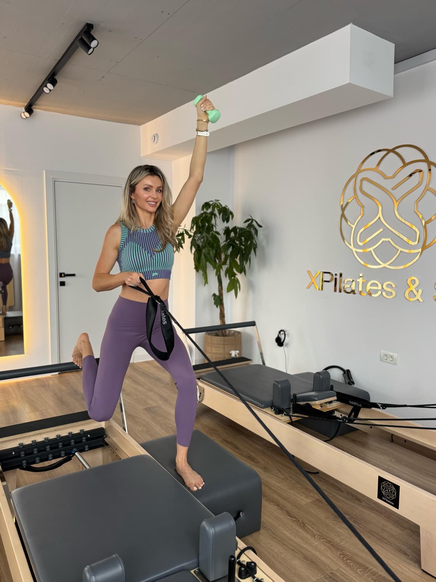Instructor XPilates explicând un exercițiu Pilates Reformer unei începătoare