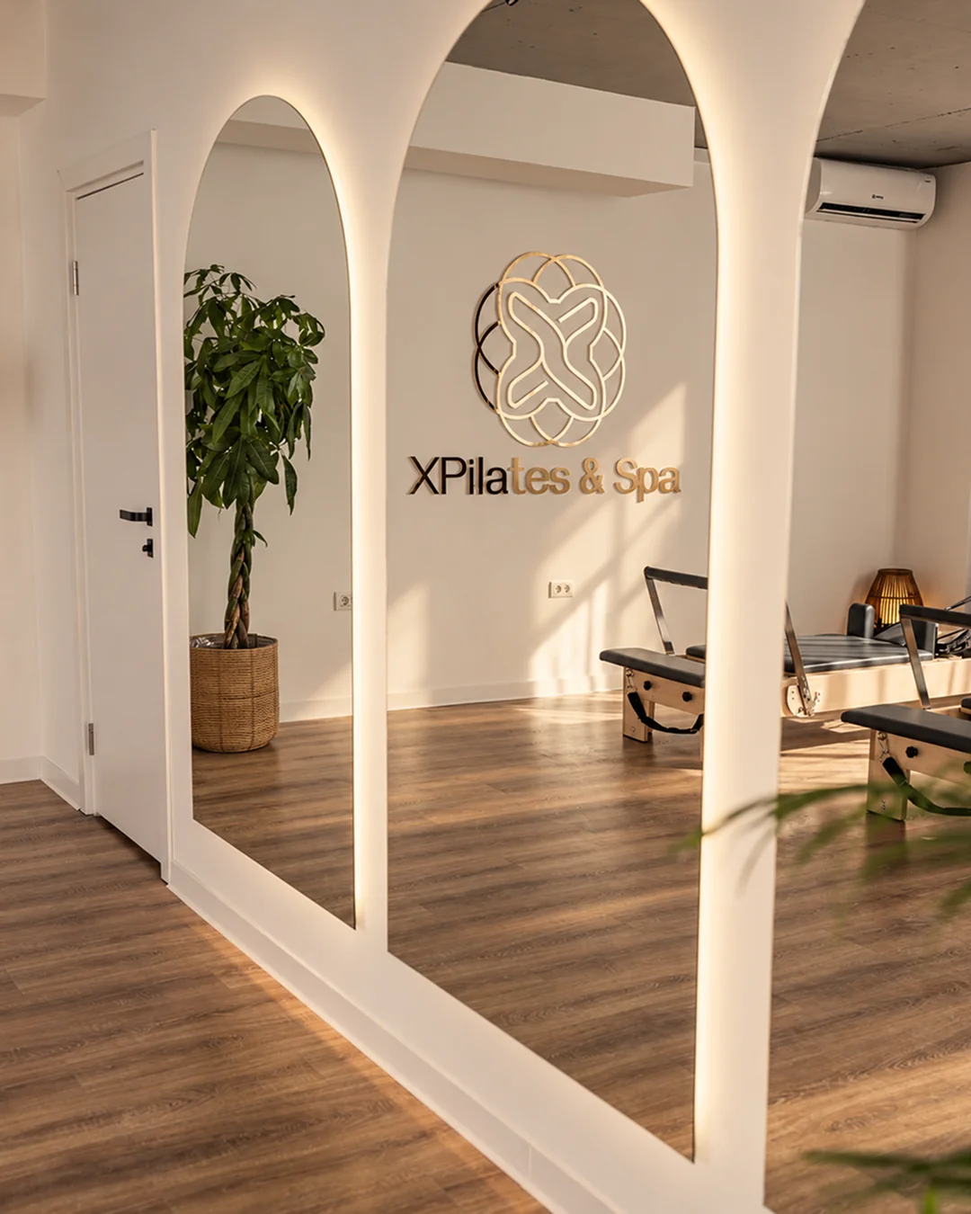 Oglinzile arcuite și sigla XPilates & Spa în studioul Pilates Reformer